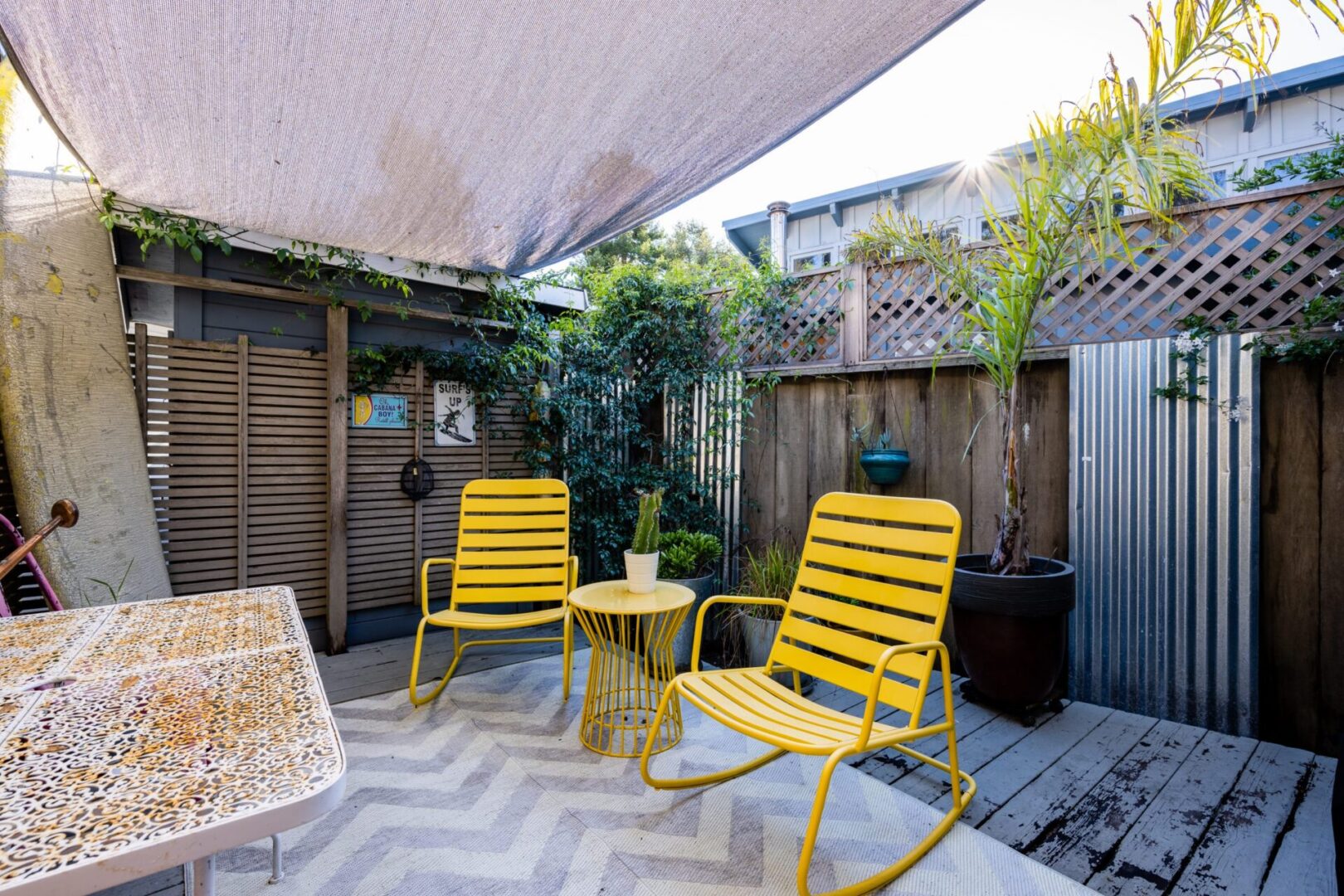 A patio with yellow chairs and an umbrella.