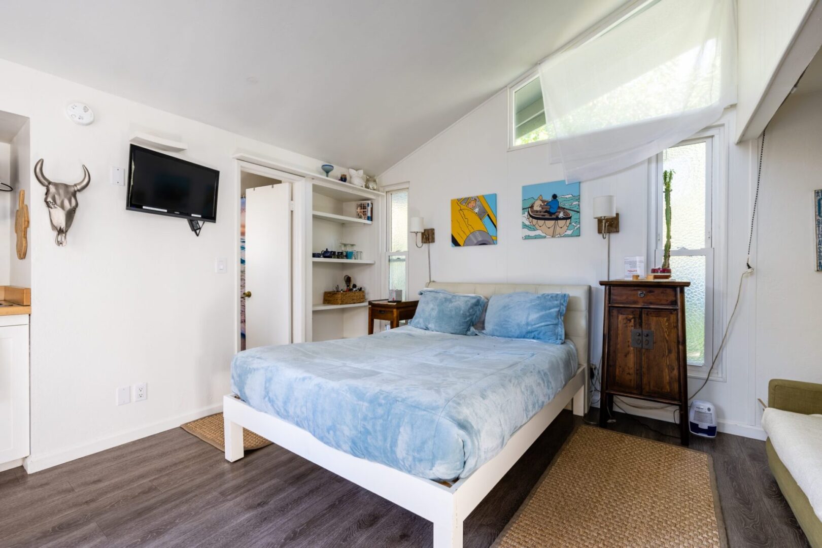 A bedroom with a bed, dresser and television.