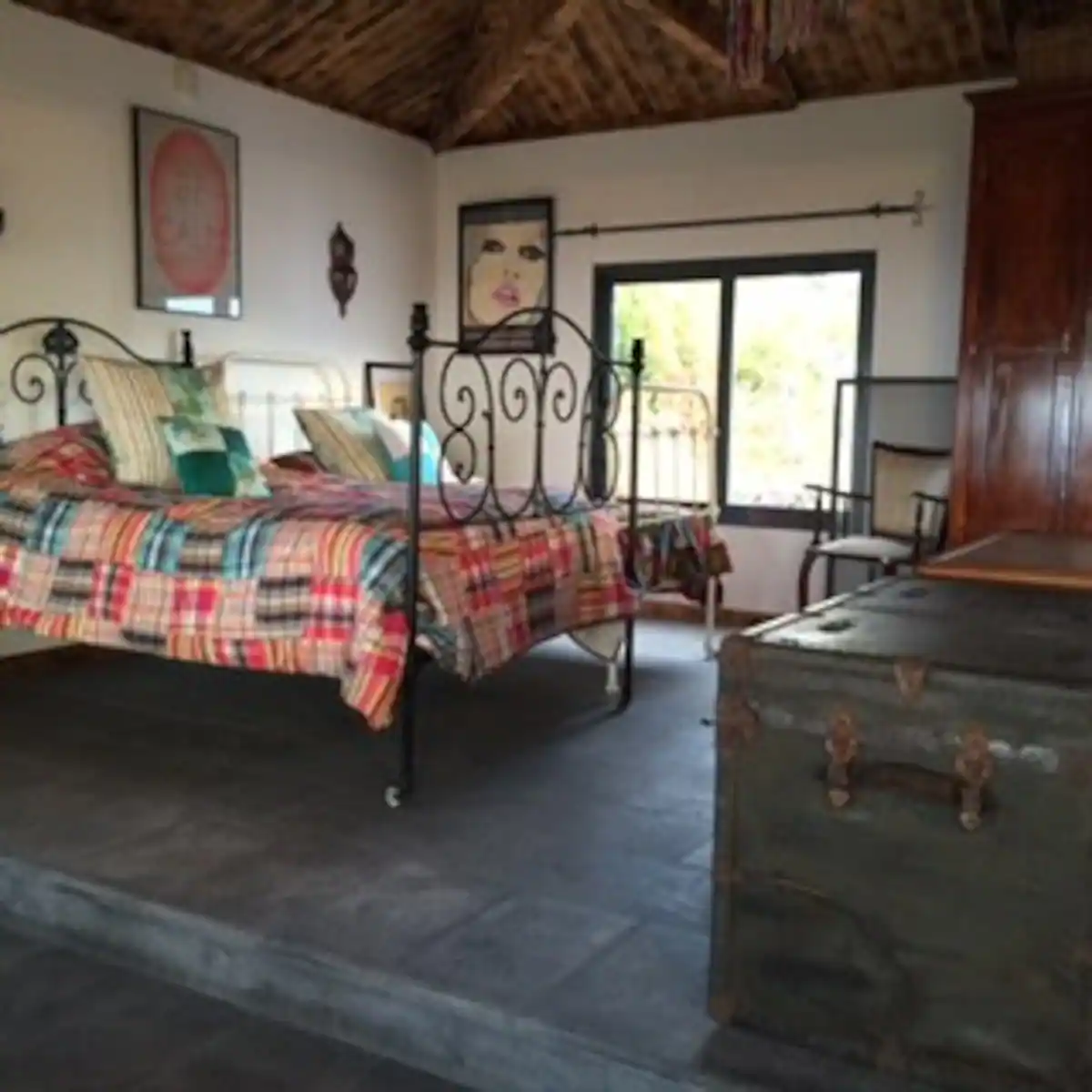 A bedroom with a bed, dresser and window.