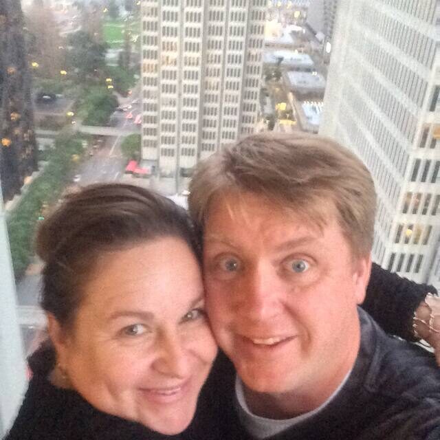 A man and woman taking a selfie in front of the city.