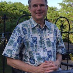 A man in a blue and white shirt is smiling.