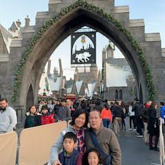 A family posing for a picture in front of the entrance to hogwarts castle.